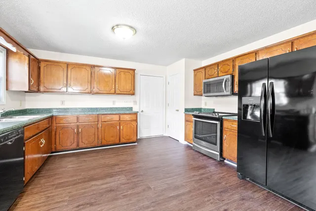 a kitchen with stainless steel appliances kitchen island granite countertop a stove a sink and a refrigerator