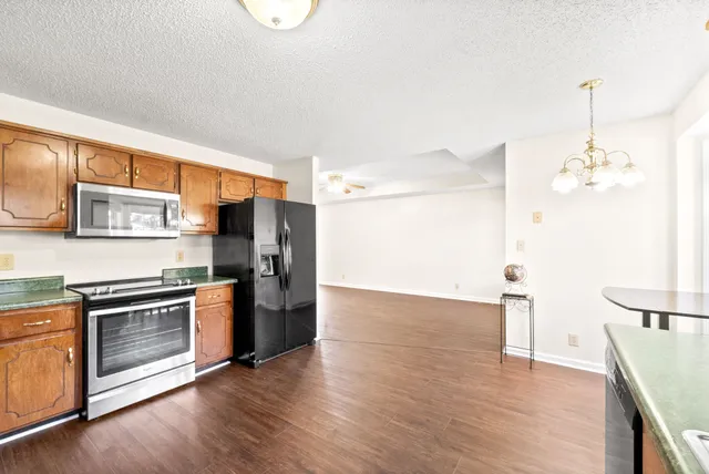 a kitchen with stainless steel appliances granite countertop a refrigerator a stove and a wooden floors