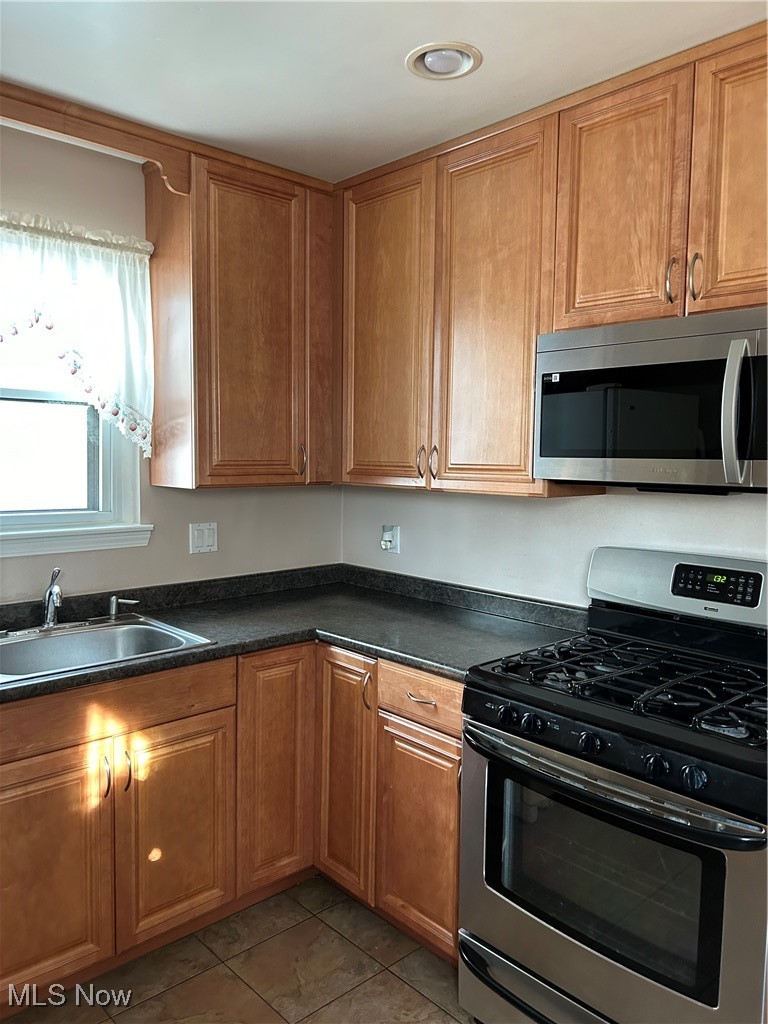 1094 Plainfield Road Cleveland, OH 44121 - Photo 7 of 41 Kitchen featuring light tile patterned flooring, stove, and sink