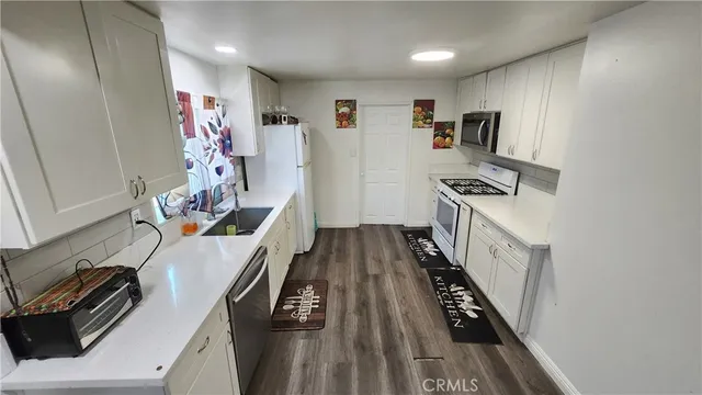a view of a kitchen with fridge and wooden floor