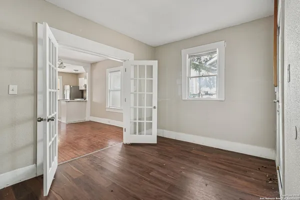 an empty room with wooden floor and windows