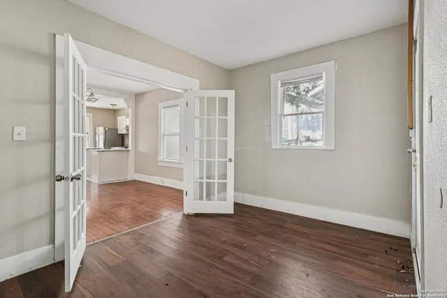 an empty room with wooden floor and windows