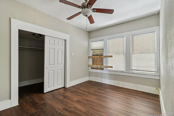 an empty room with wooden floor closet and windows