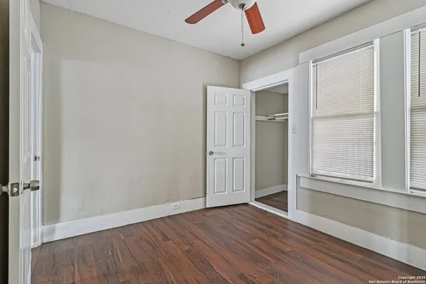 an empty room with wooden floor and windows