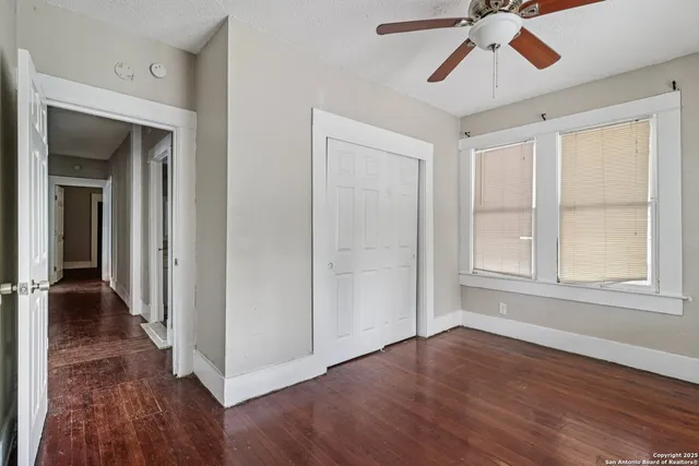 a view of empty room with wooden floor and fan