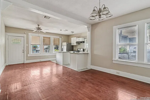 a view of an empty room with kitchen and window