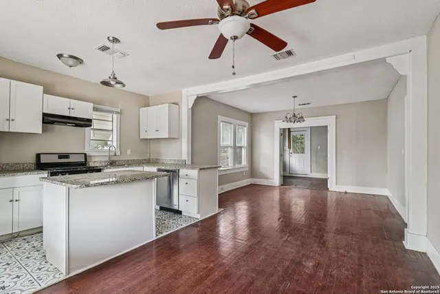 a kitchen with stainless steel appliances granite countertop a sink cabinets and wooden floor