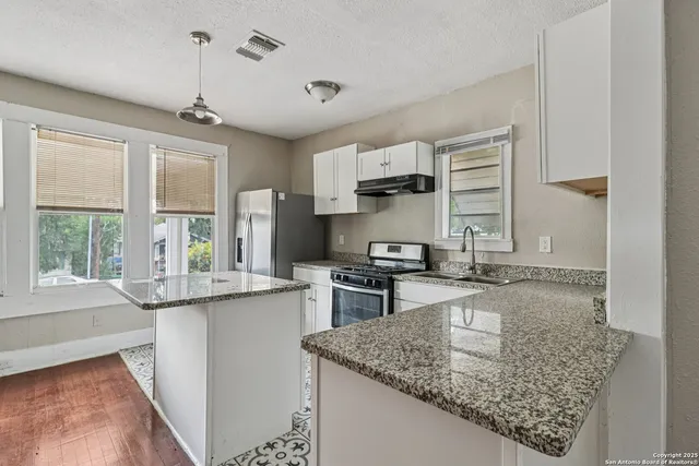 a kitchen with kitchen island granite countertop a sink stove and cabinets