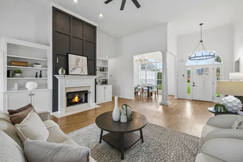 a living room with stainless steel appliances furniture a fireplace and a chandelier