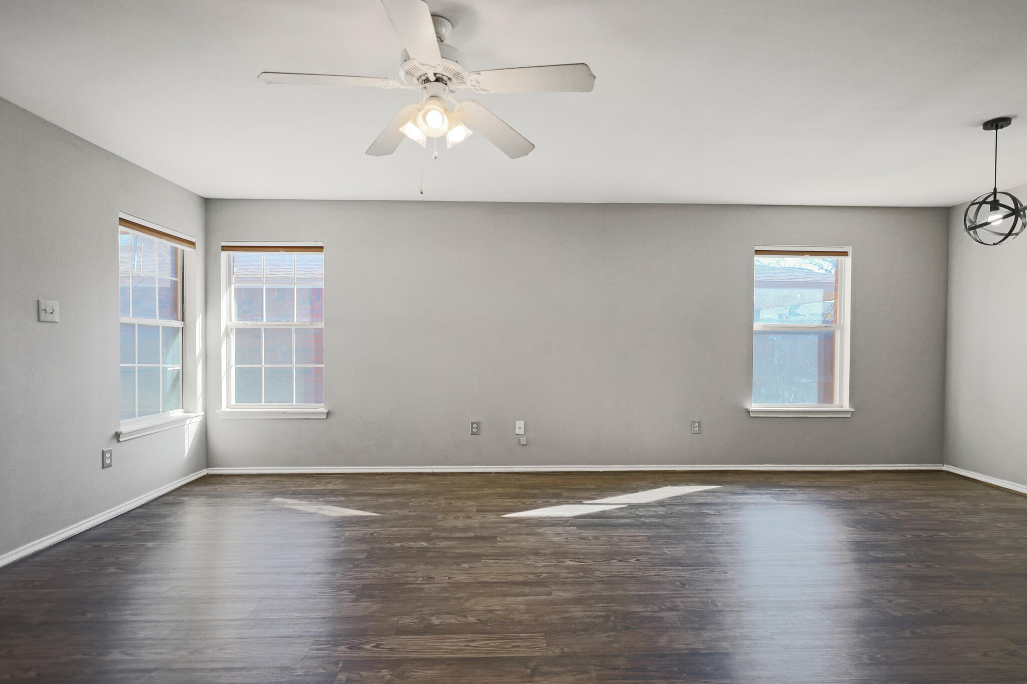 5903 10th Street, Unit 2 Lubbock, TX 79416 - Photo 4 of 47 an empty room with wooden floor chandelier fan and windows