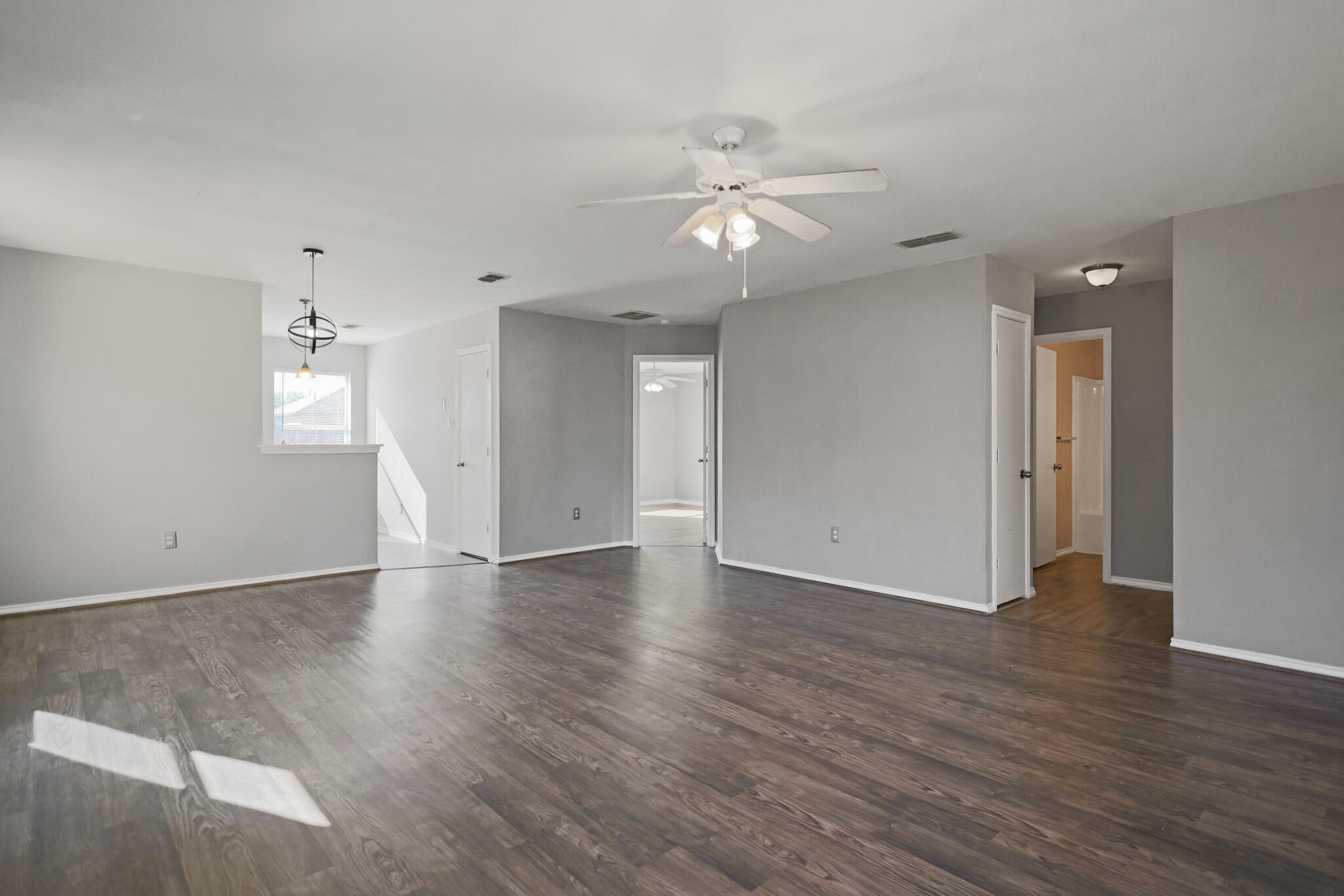 5903 10th Street, Unit 2 Lubbock, TX 79416 - Photo 9 of 47 an empty room with wooden floor chandelier fan and windows