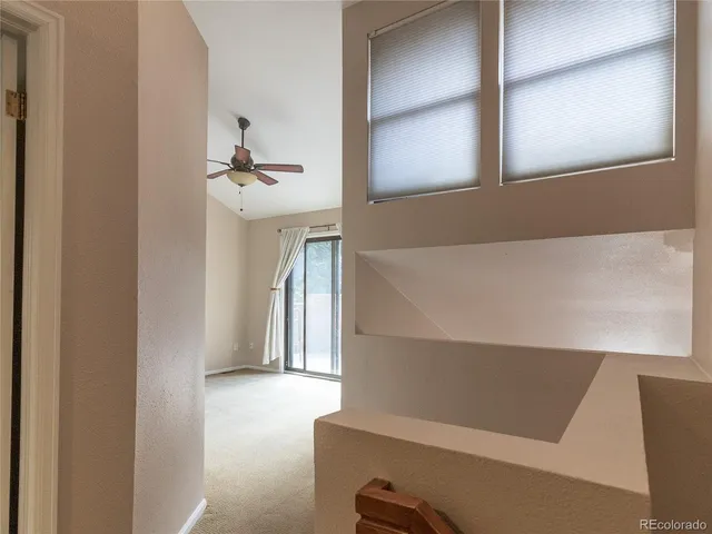 an empty room with windows and a ceiling fan