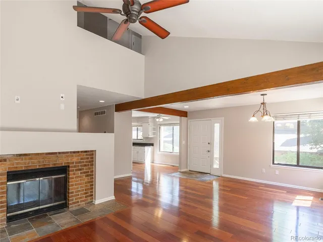 a view of an empty room with wooden floor and a fireplace