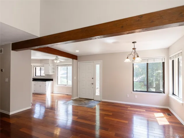 a view of an empty room with wooden floor and a window