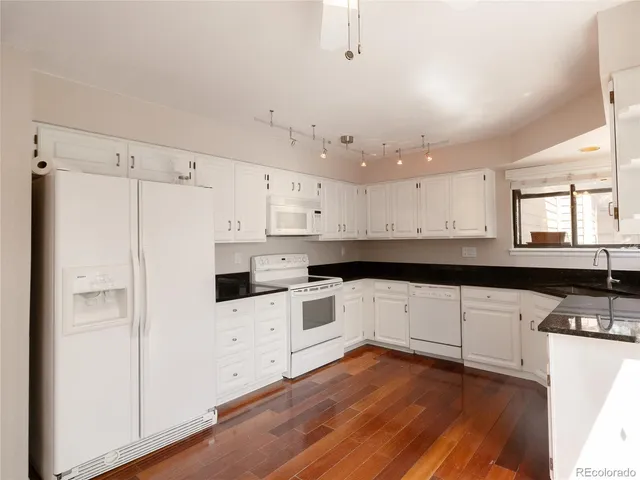 a kitchen with granite countertop white cabinets and white appliances