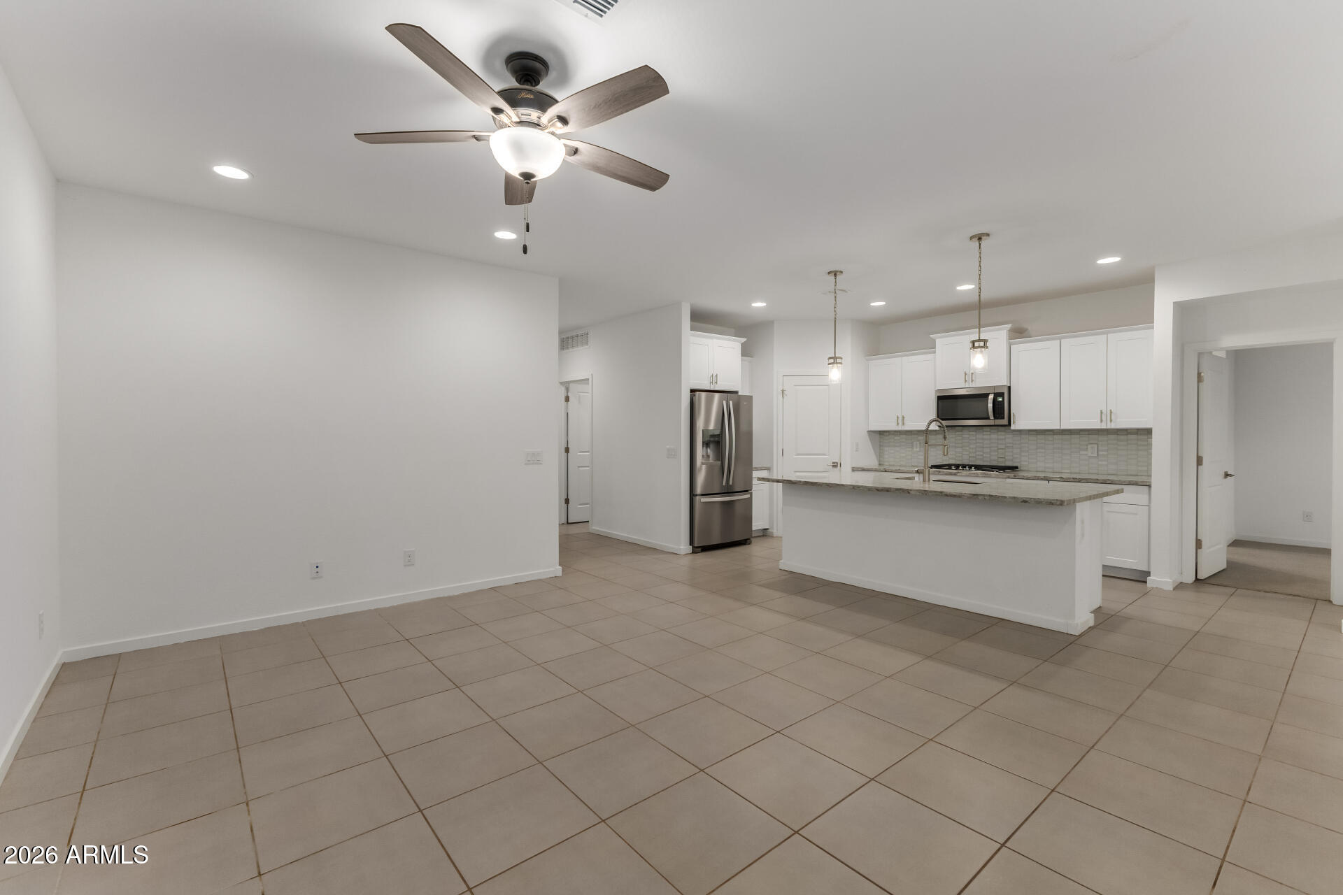 4337 East Italian Trotter Road San Tan Valley, AZ 85140 - Photo 10 of 35 a large white kitchen with kitchen island a stove a sink a refrigerator and white cabinets with wooden floor