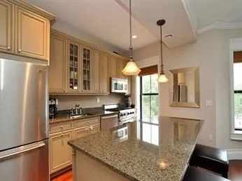 a kitchen with stainless steel appliances granite countertop a refrigerator a sink dishwasher a stove and a dining table with wooden floor