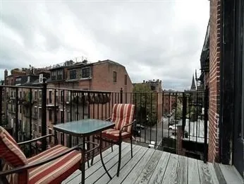 a view of a roof deck with table and chairs a barbeque with wooden floor and fence