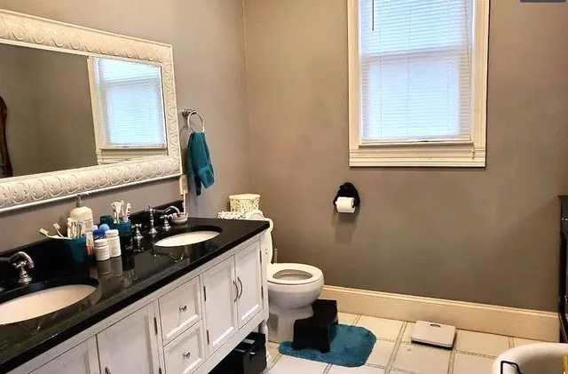 a bathroom with a granite countertop sink a toilet and a mirror