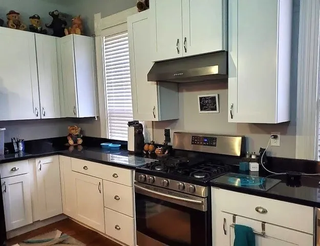 a kitchen with granite countertop white cabinets and white appliances