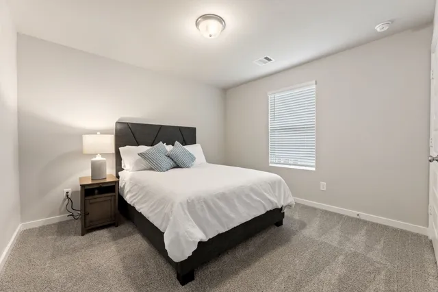a bed sitting in a spacious bedroom next to a window