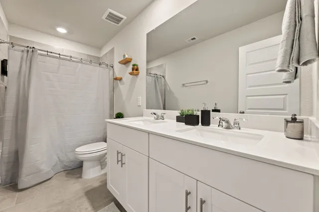a bathroom with double vanity sink a mirror and a toilet
