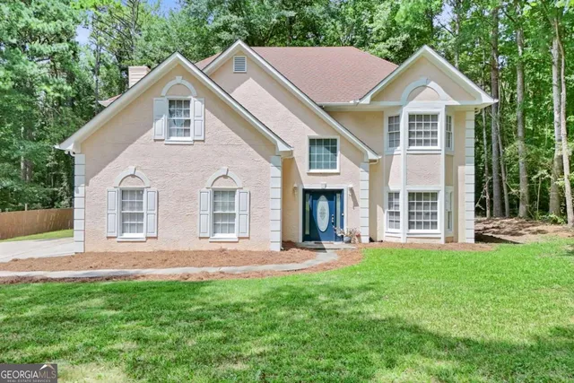 a front view of a house with a yard and trees