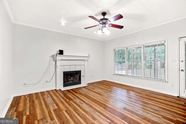 a view of a livingroom with a fireplace a ceiling fan and wooden floor