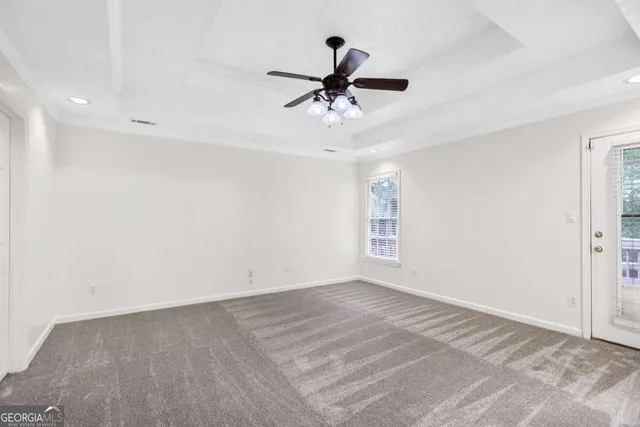 an empty room with windows and fan