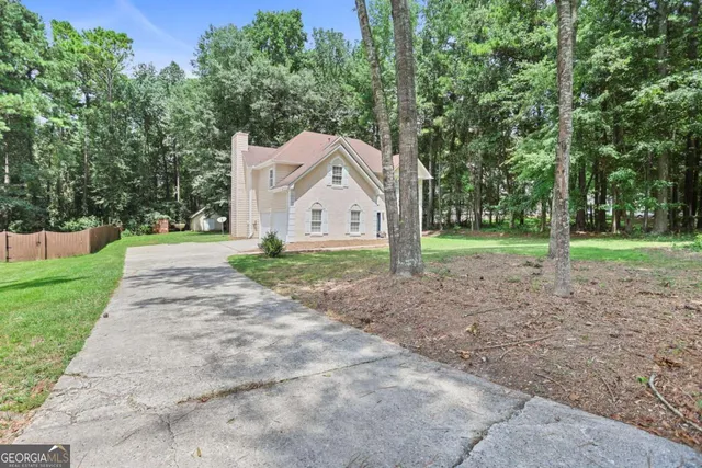 a view of a white house with a big yard and large trees