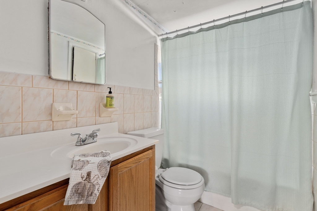 30 Wampum Avenue Waltham, MA 02451 - Photo 22 of 29 a bathroom with a sink a toilet and shower curtain