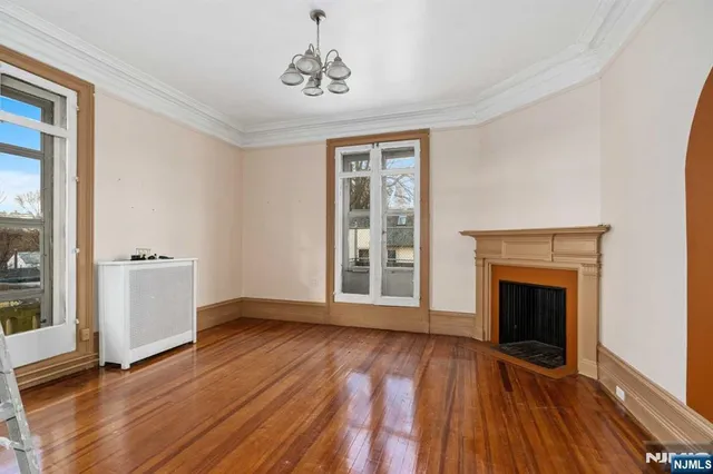 an empty room with windows fireplace and wooden floor