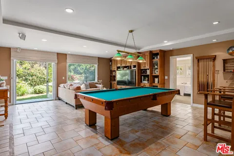 a room with pool table and large windows