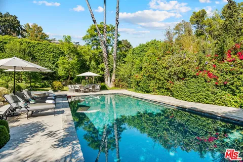 a backyard of a house with table and chairs under an umbrella