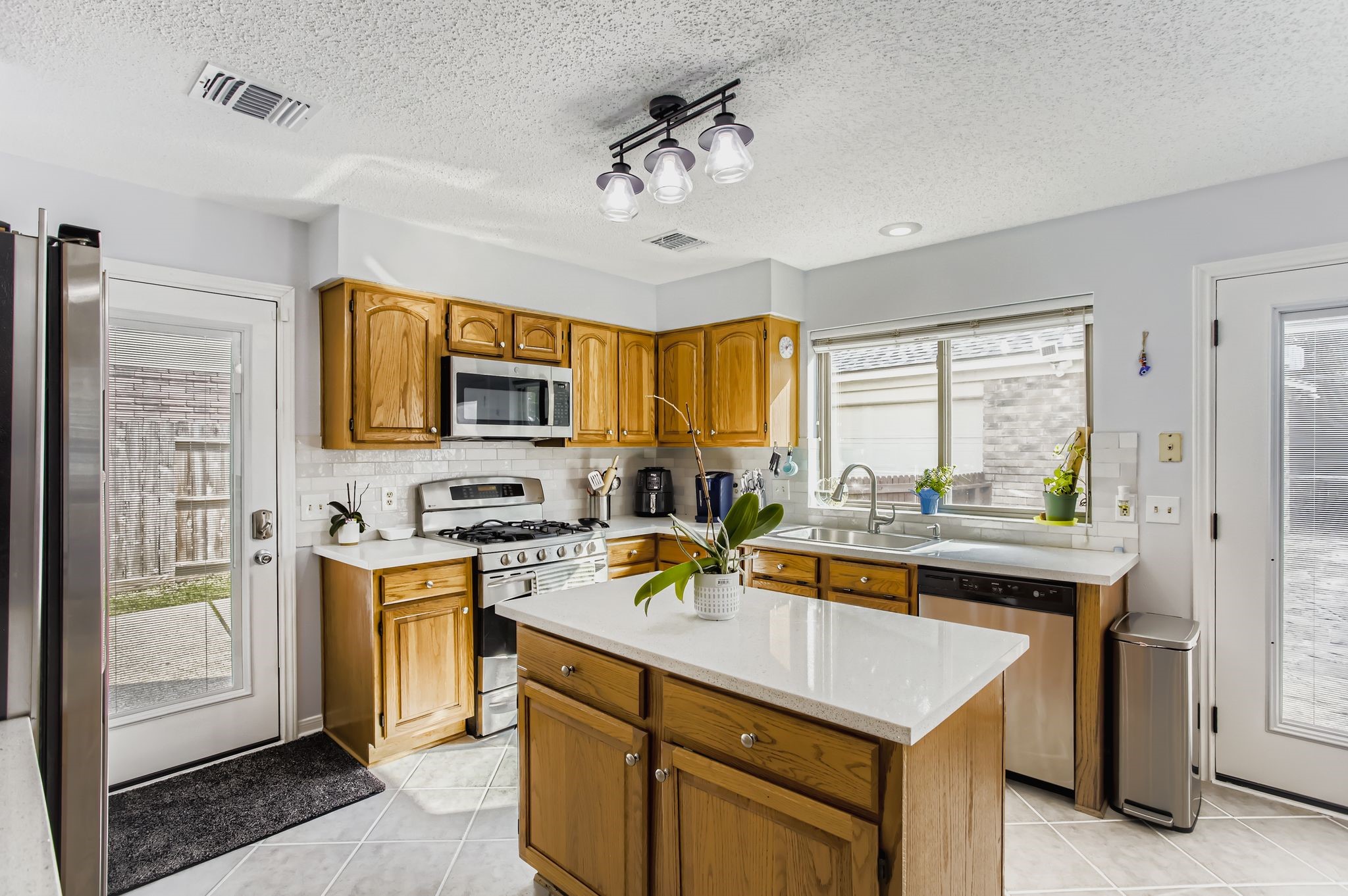 7530 Dogwood Falls Road Houston, TX 77095 - Photo 12 of 27 The kitchen has been updated with quartz countertops, modern tile backsplash, updated lighting, brand new dishwasher and new side and double back doors with between-the-glass blinds.