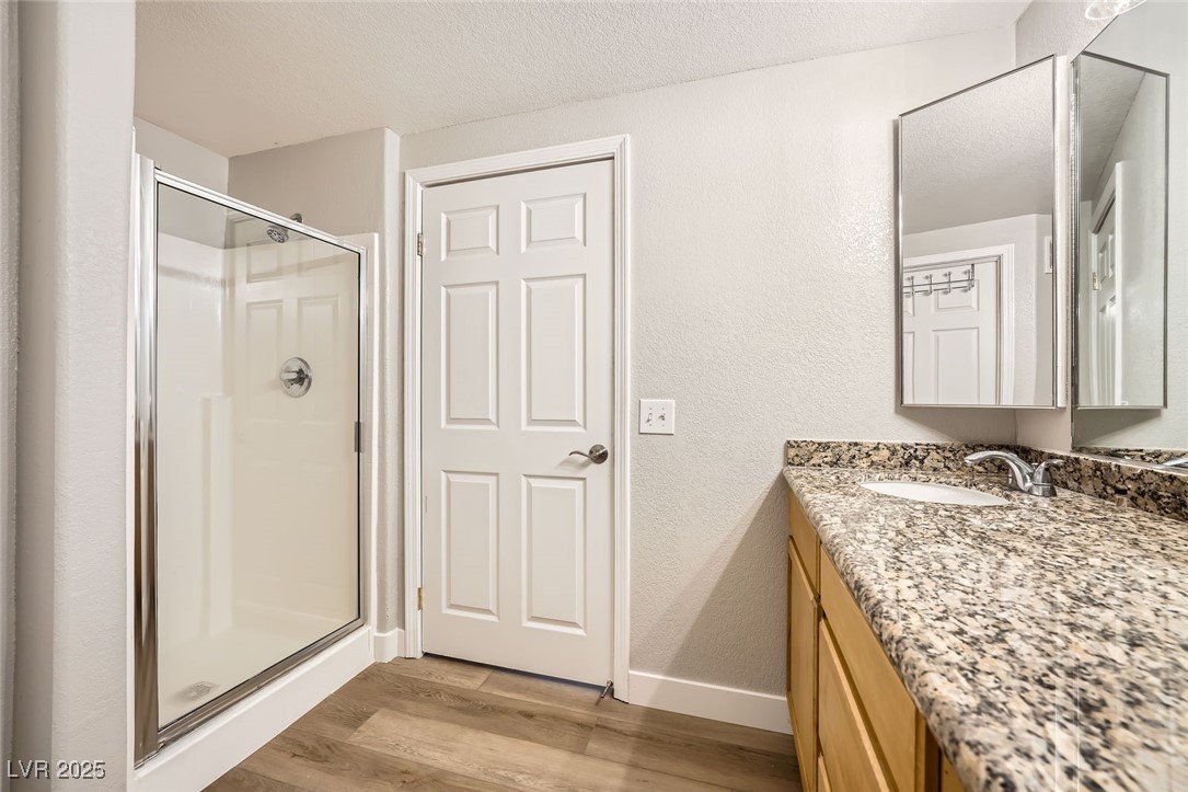 10550 West Alexander Road, Unit 2179 Las Vegas, NV 89129 - Photo 17 of 28 Full bathroom featuring baseboards, vanity, wood finished floors, and a shower stall