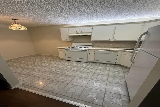 a kitchen with a sink a stove cabinets and utility