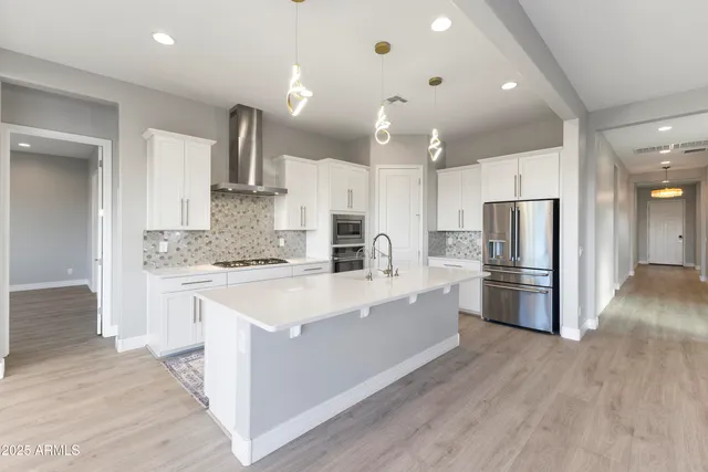 a large white kitchen with kitchen island a sink a center island stainless steel appliances and a cabinets