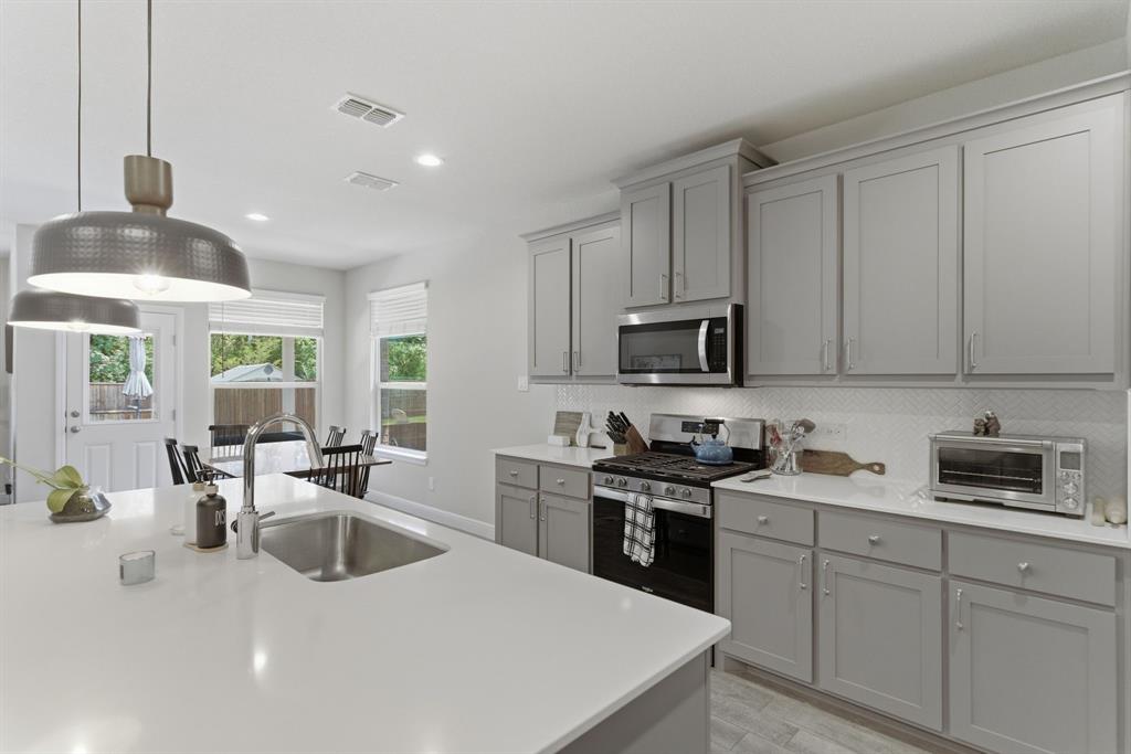 5621 Round Hl Road Denton, TX 76210 - Photo 8 of 27 a kitchen with stainless steel appliances a sink a stove a microwave a center island and cabinets