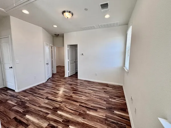a view of an empty room with wooden floor and a window