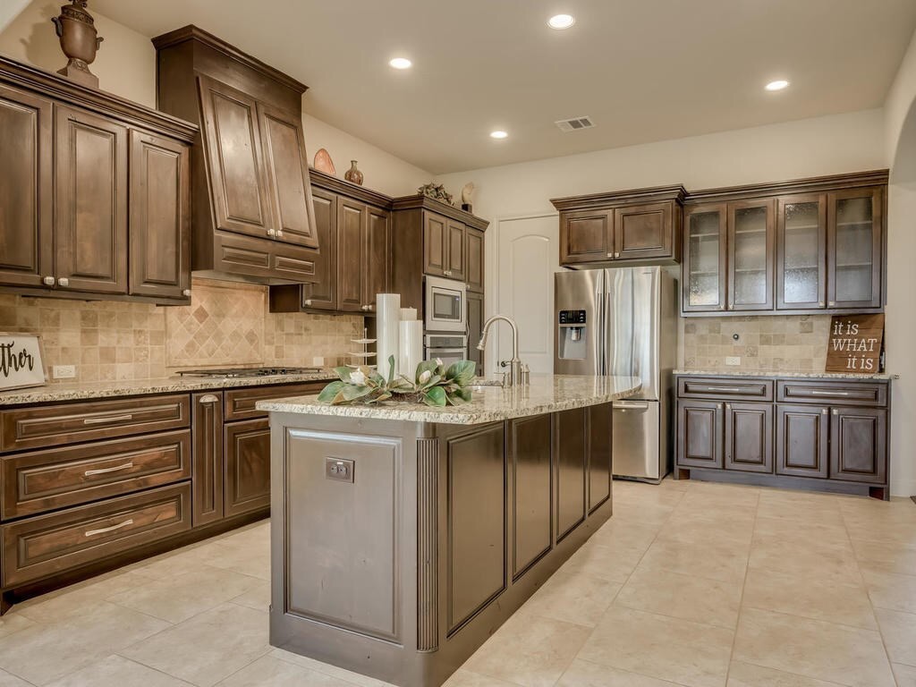 12912 Schleicher Trail Austin, TX 78732 - Photo 12 of 39 a kitchen with stainless steel appliances granite countertop a stove refrigerator and cabinets