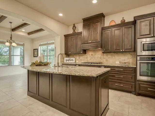a kitchen with stainless steel appliances granite countertop a refrigerator a stove and a sink
