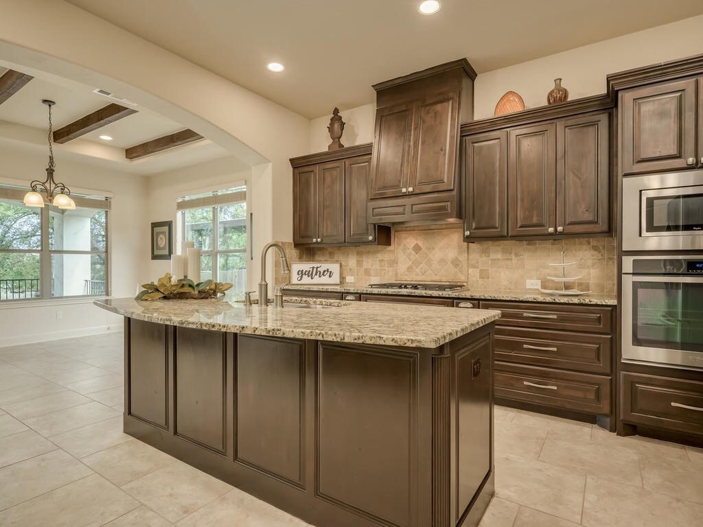 12912 Schleicher Trail Austin, TX 78732 - Photo 14 of 39 a kitchen with granite countertop a sink stove and cabinets