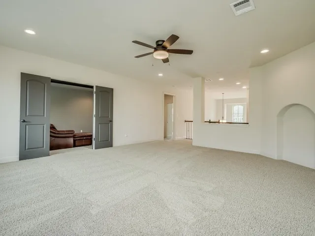 an empty room with windows chandelier fan and windows