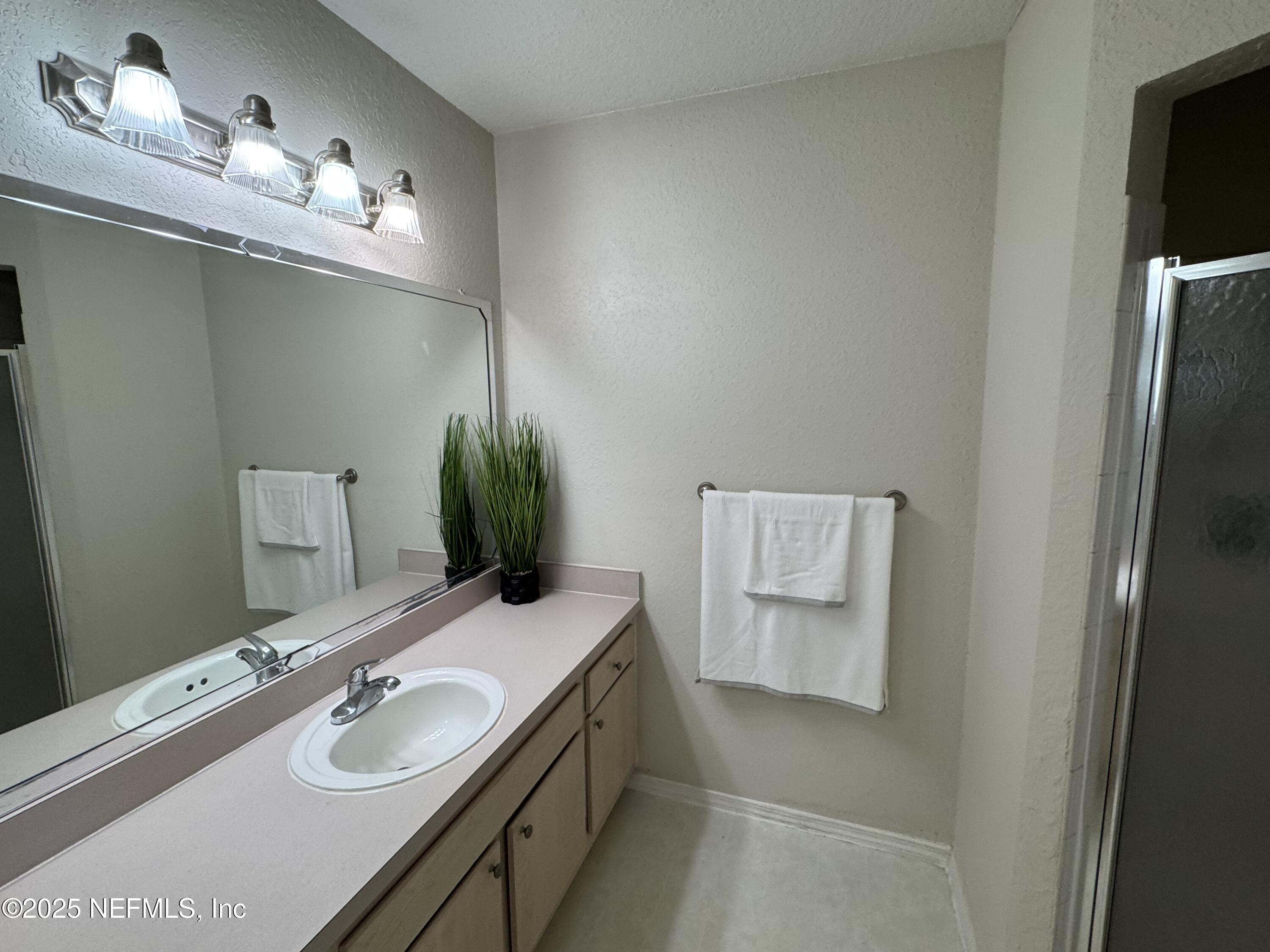 1701 The Greens Way, Unit 214 Jacksonville Beach, FL 32250 - Photo 12 of 21 a bathroom with a double vanity sink and mirror