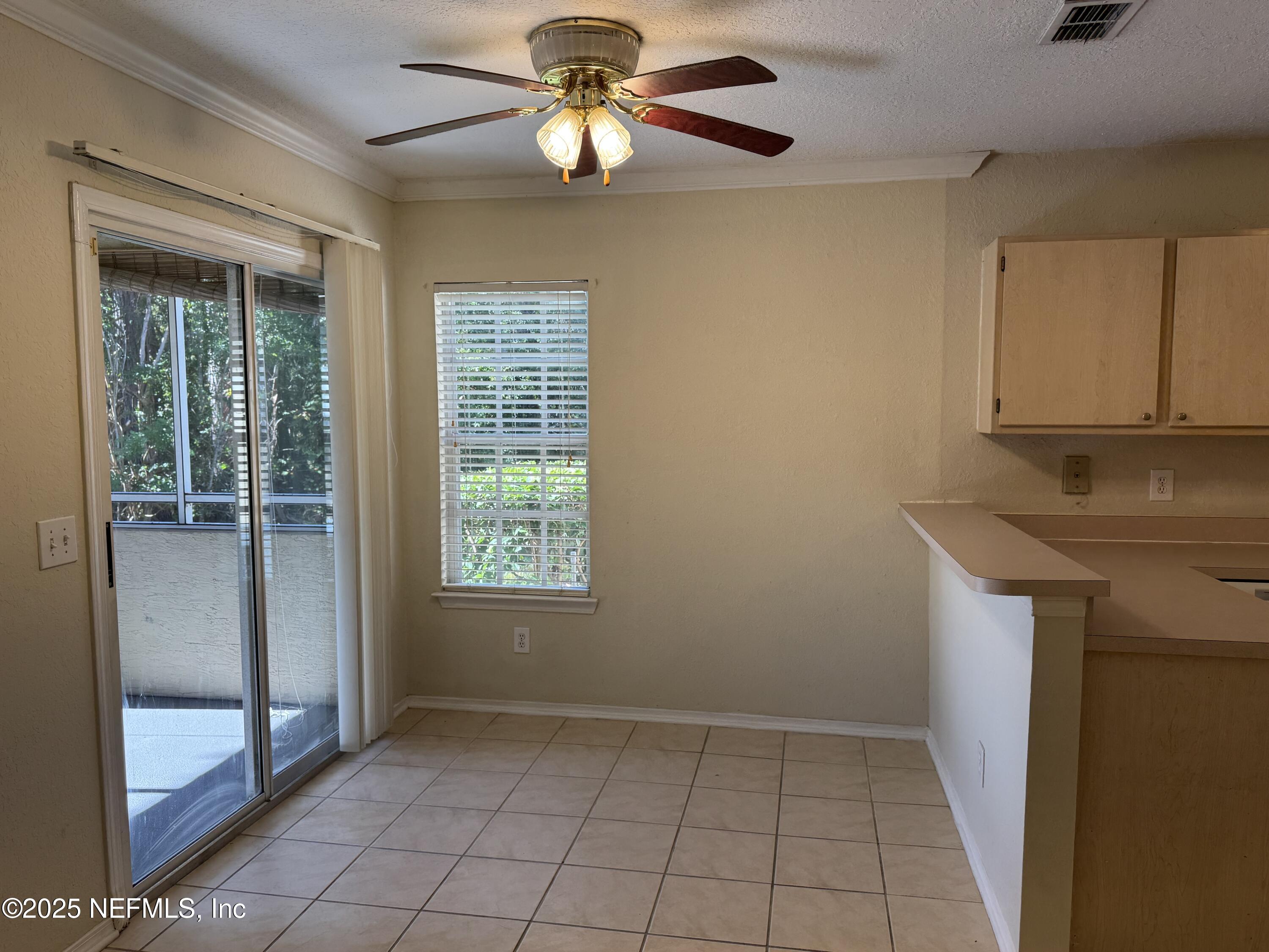 1701 The Greens Way, Unit 214 Jacksonville Beach, FL 32250 - Photo 8 of 21 a view of an empty room with window and chandelier fan