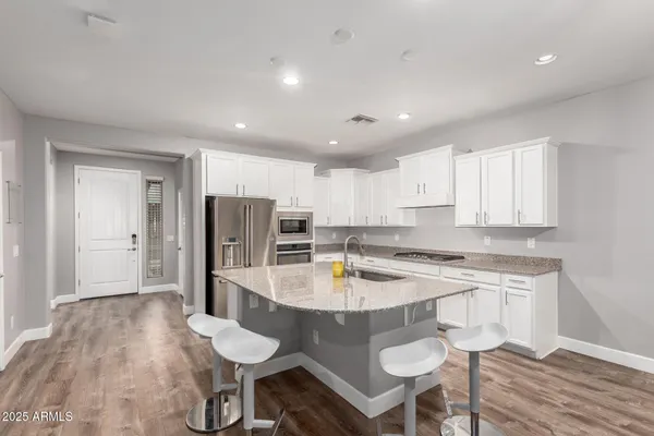 a kitchen with refrigerator and wooden floor