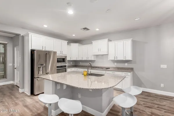 a kitchen with stainless steel appliances granite countertop a sink a stove a refrigerator and cabinets