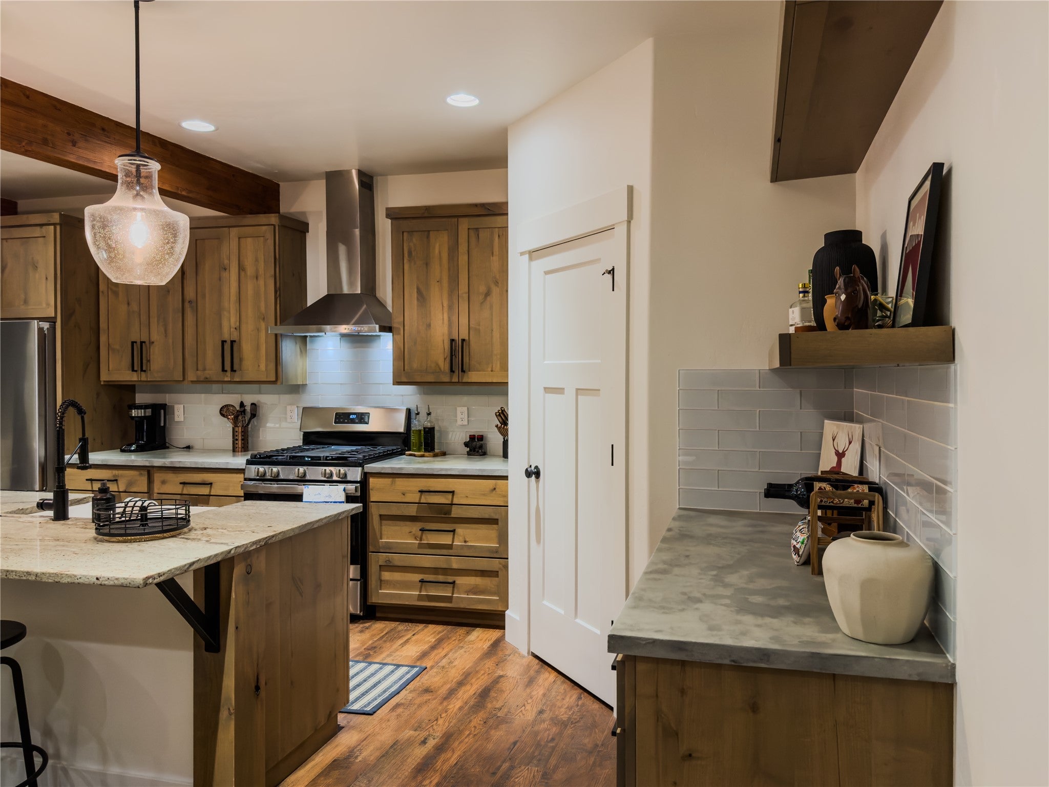 717 Icehouse Road Whitefish, MT 59937 - Photo 8 of 31 Kitchen featuring tasteful backsplash, wall chimney exhaust hood, a kitchen bar, appliances with stainless steel finishes, and brown cabinetry