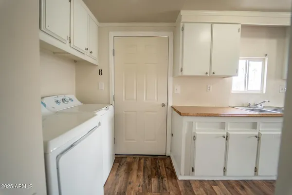 a utility room with a sink a cabinetry and a washer dryer